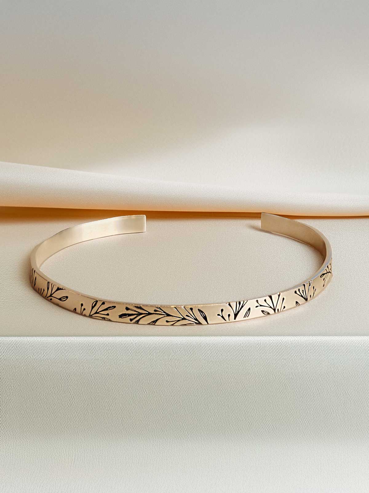 a close up of a gold bracelet on a white surface