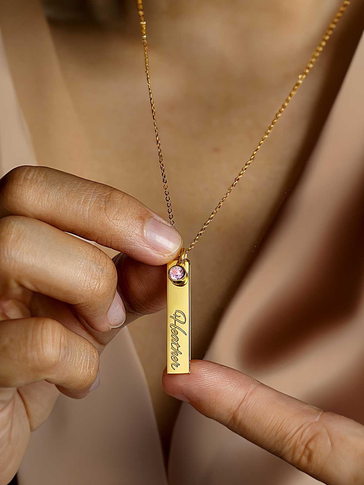 a woman holding a necklace with a name tag on it