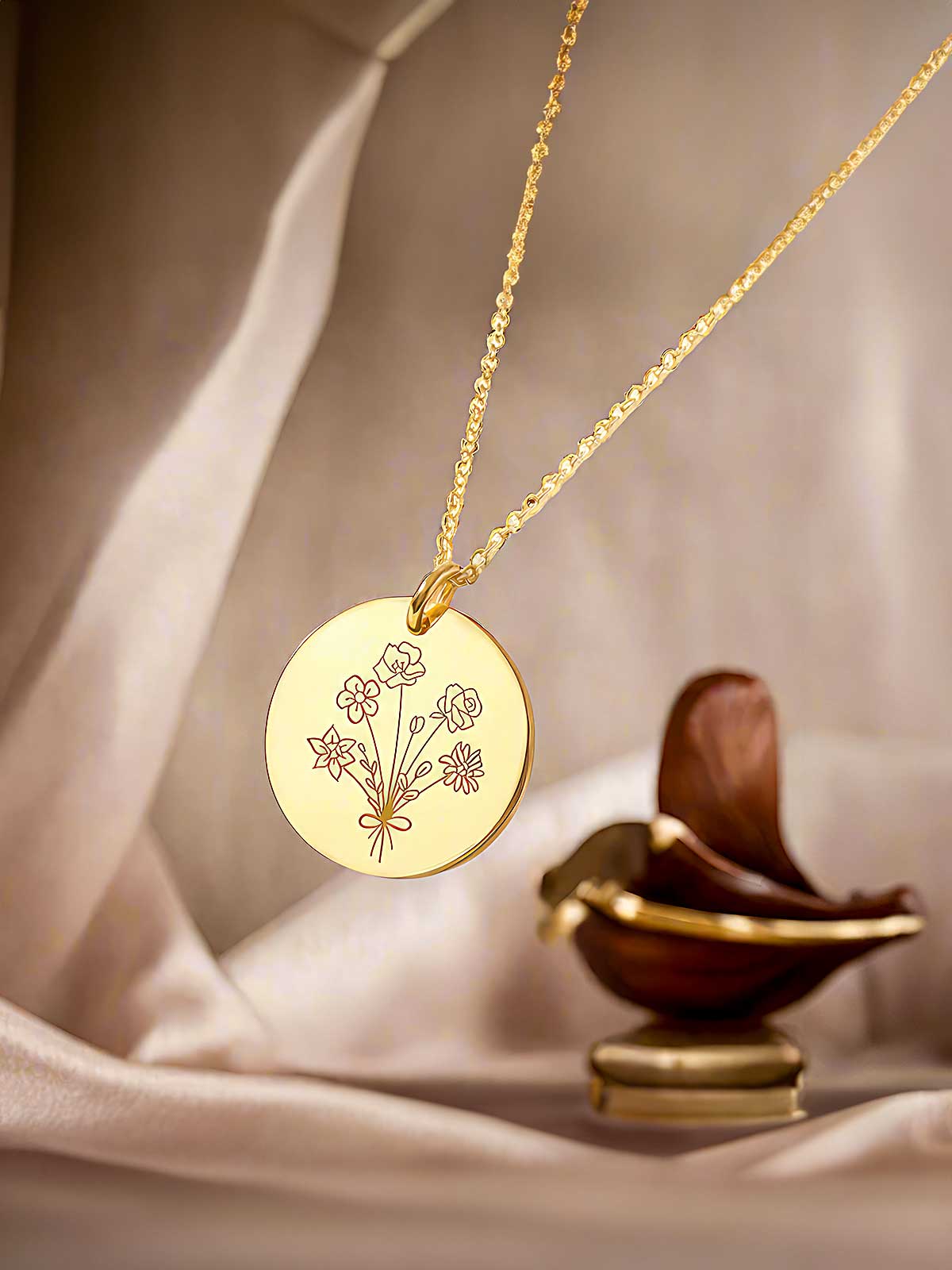 a gold necklace with a flower engraved on it