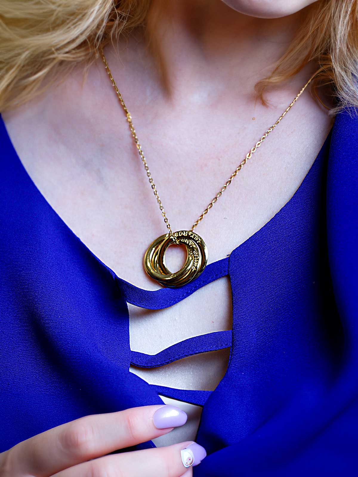 a woman wearing a blue dress holding a gold necklace