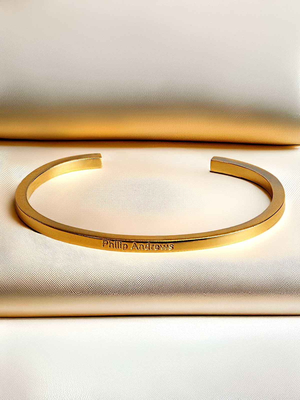 a close up of a gold bracelet on a white surface