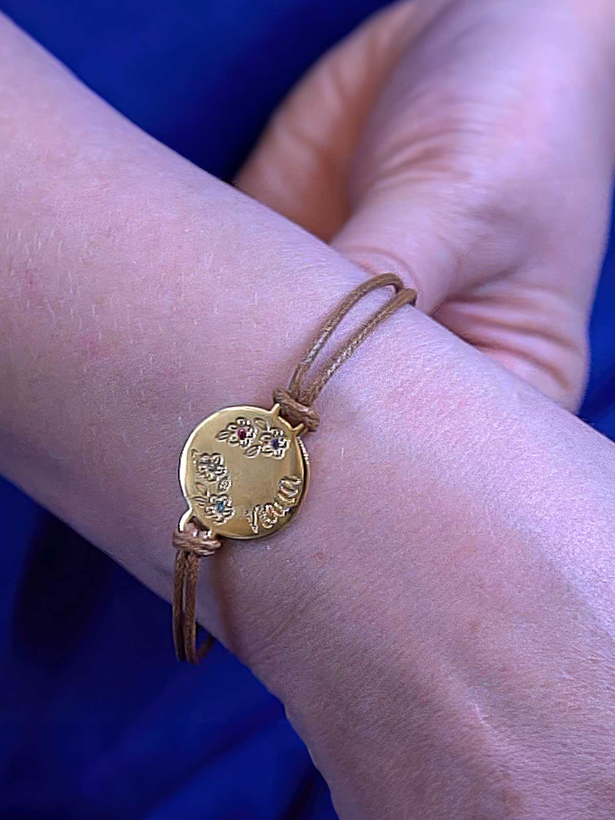 a person wearing a bracelet with a gold disc on it