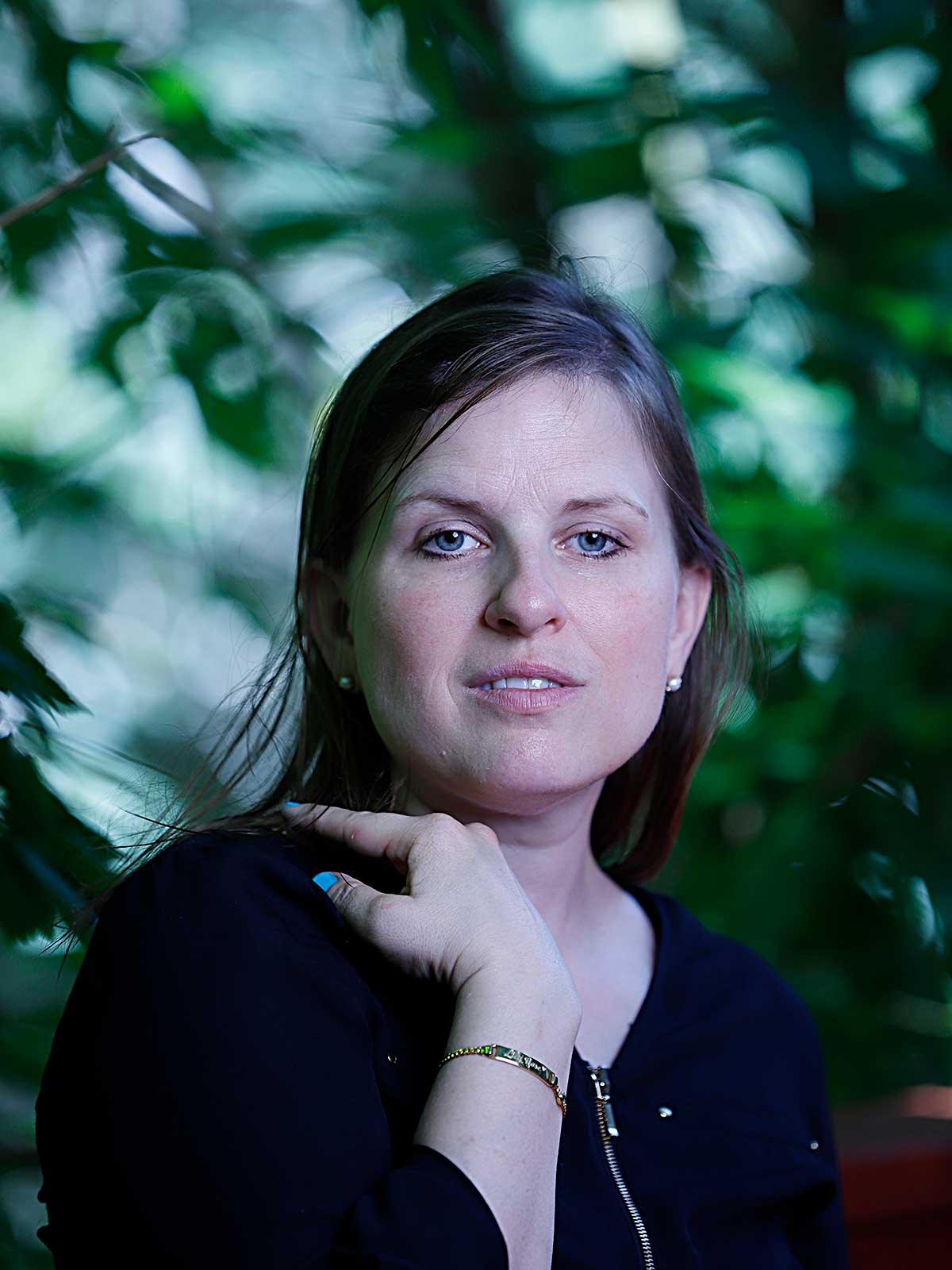 a woman is posing for a picture in front of a tree