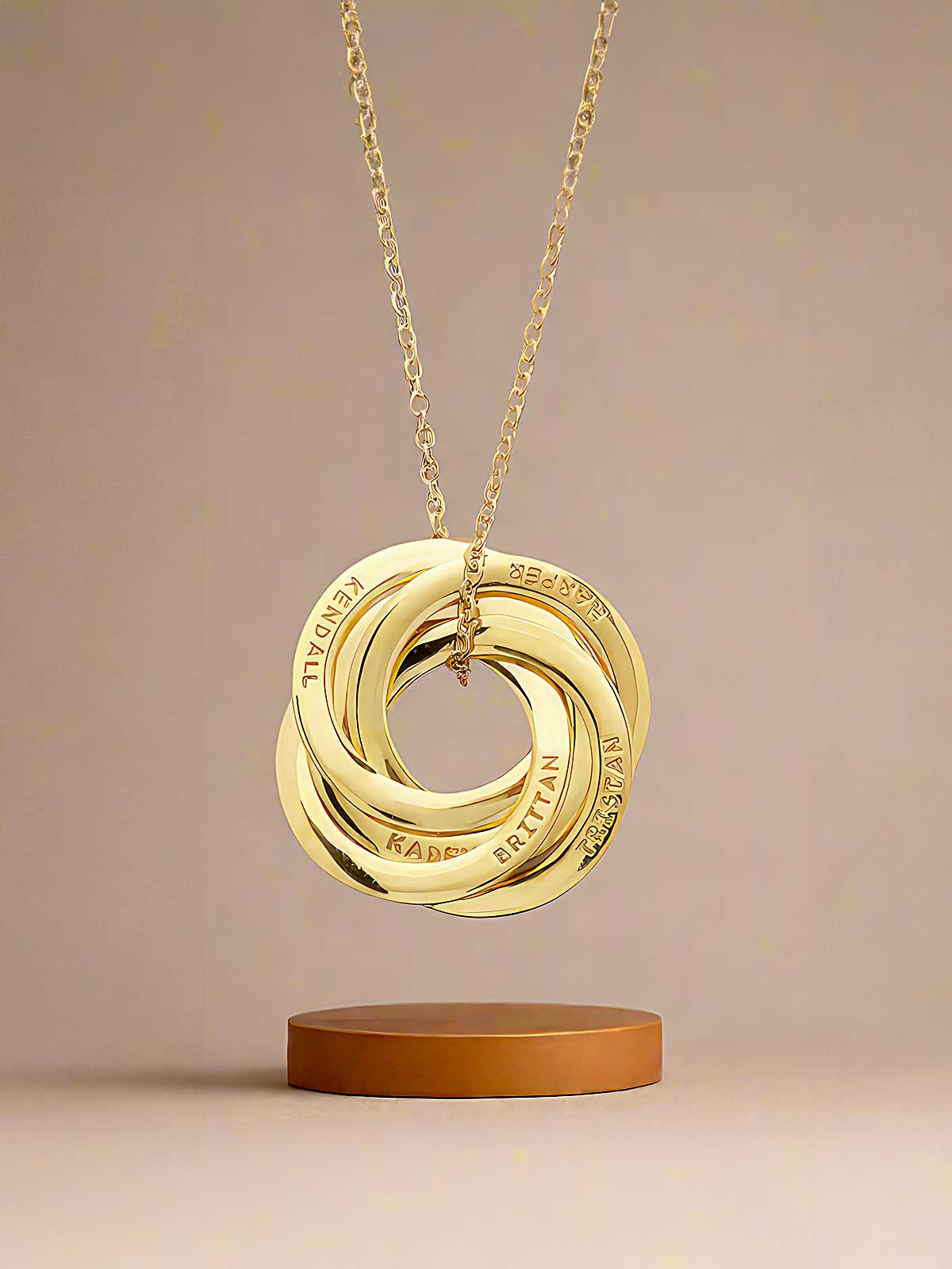 a gold necklace with three interlocked circles on a wooden stand