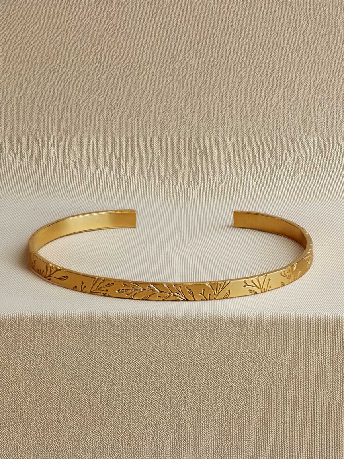 a close up of a gold bracelet on a beige surface