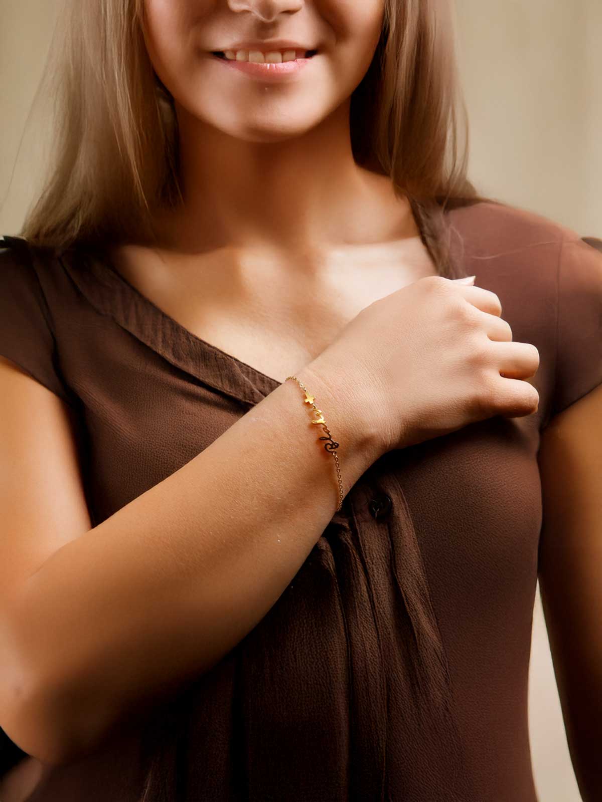 a woman wearing a brown shirt and a gold bracelet