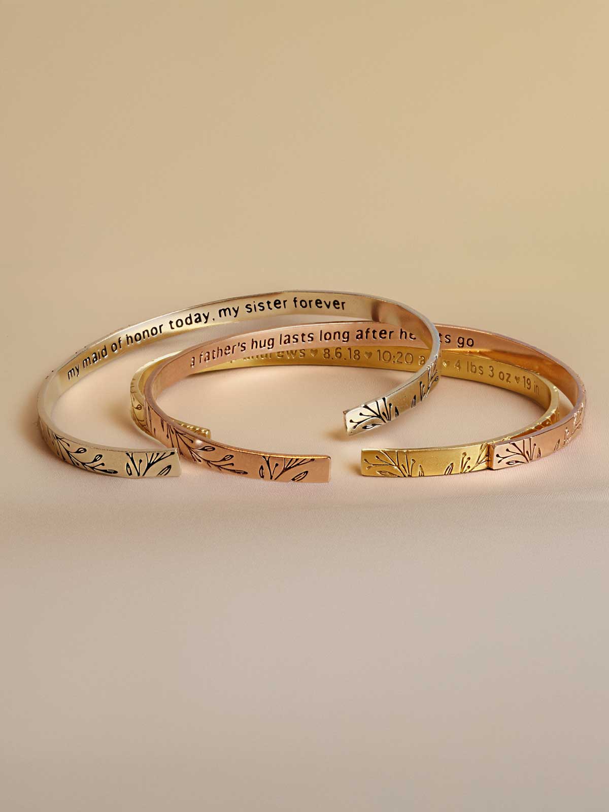 three gold bracelets with words written on them